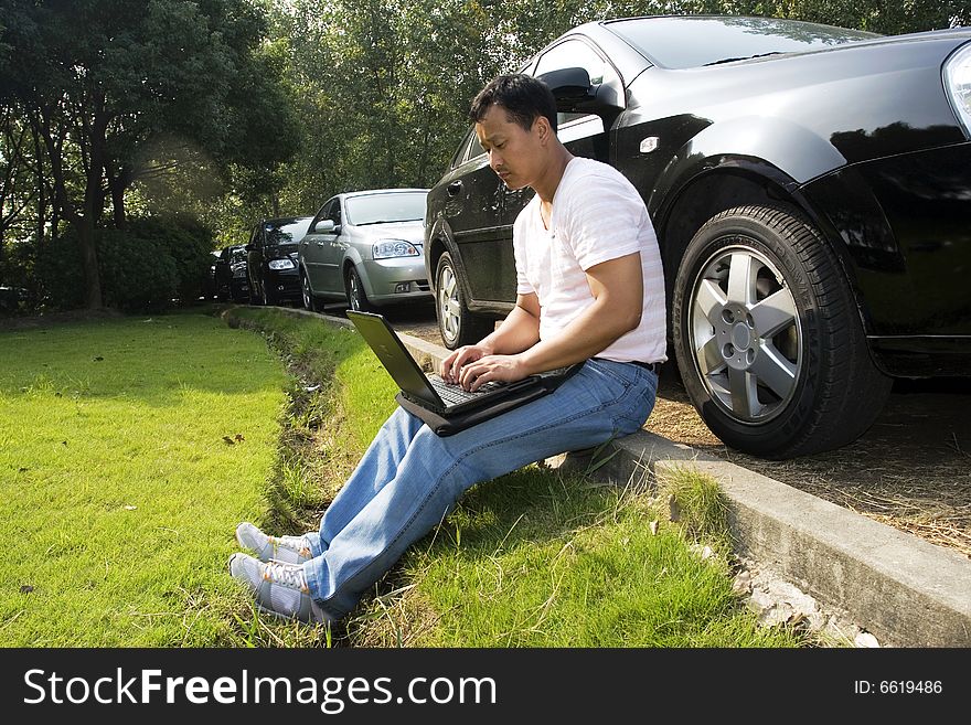 The man working outdoors with a laptop.