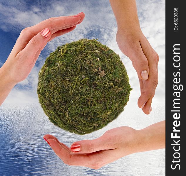 Recycling symbol made from hands; cloudy blue sky and ocean as a background