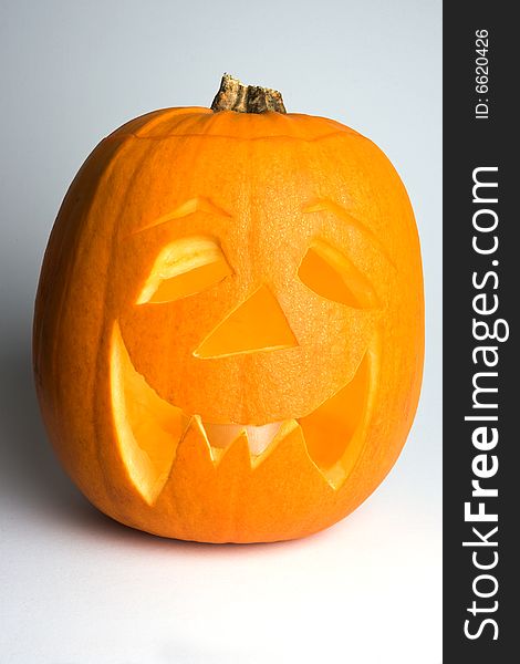 A carved halloween 'Jack 'o' Lantern' pumpkin, with internal candle. Set on a white background with left-hand side in partial shadow. A carved halloween 'Jack 'o' Lantern' pumpkin, with internal candle. Set on a white background with left-hand side in partial shadow.