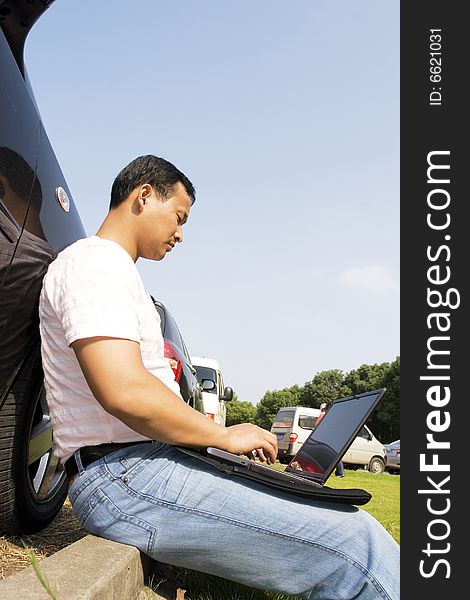 The man working outdoors with a laptop.