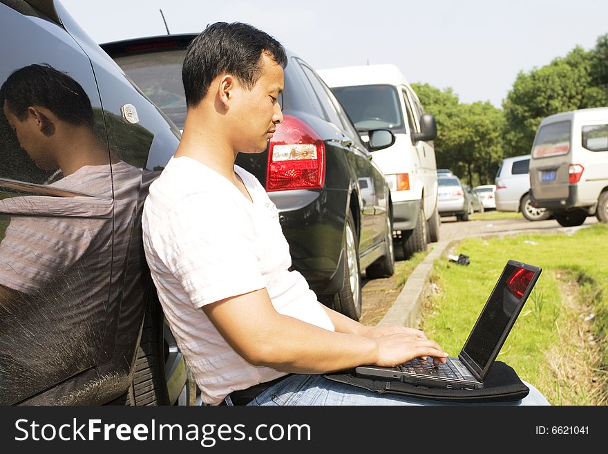 The man working outdoors with a laptop.