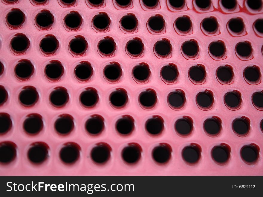 Close-up, abstract, round, holes, vent, venting, background, diagonal, metal, texture, red, ruby. Close-up, abstract, round, holes, vent, venting, background, diagonal, metal, texture, red, ruby