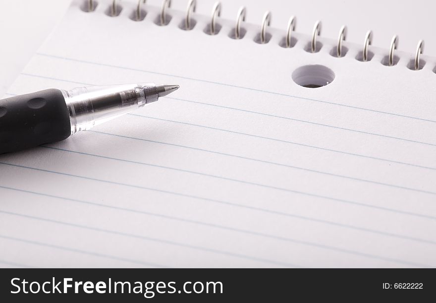 A notebook and black pen in a close up image. A notebook and black pen in a close up image.