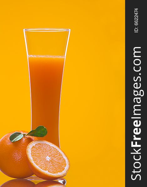 View of long glass filled with fresh juice and some oranges nearby. View of long glass filled with fresh juice and some oranges nearby