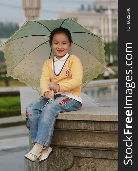 The smiling girl with a umbrella in a park .