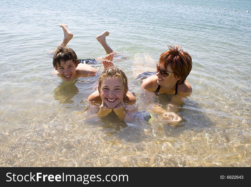 Children with mother lying on the beach and looking happy. Children with mother lying on the beach and looking happy.