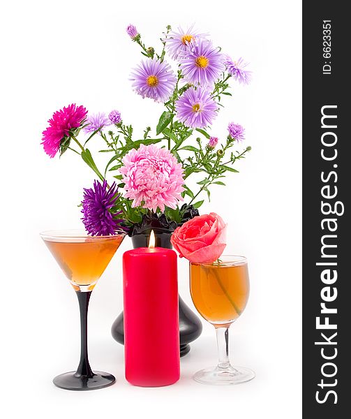 Black vase with colors and burning red candle with scarlet rose at wine-glass with wine on white background