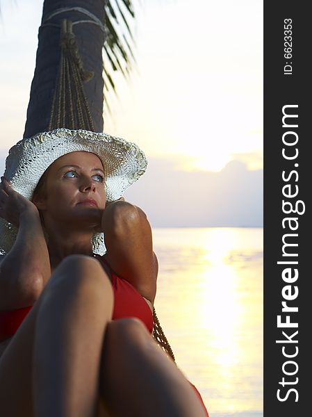 View of a woman lounging in hammock during sunset. View of a woman lounging in hammock during sunset