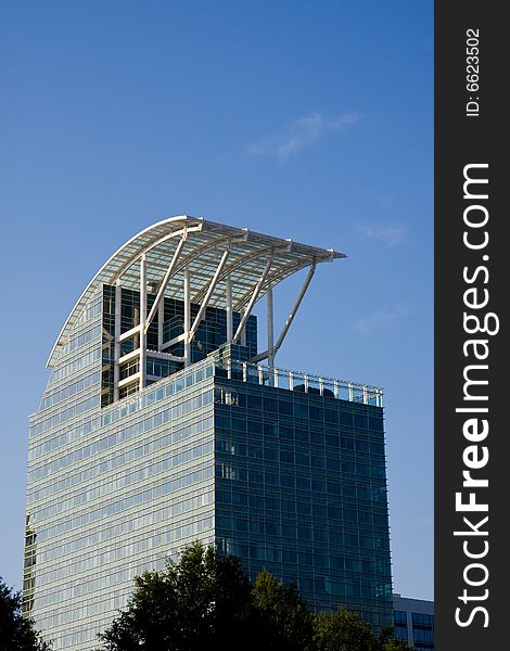 A blue glass office building with a curved roof. A blue glass office building with a curved roof