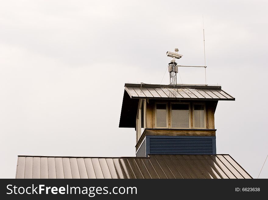 A metal roof on a seaside building with a video camera on top. A metal roof on a seaside building with a video camera on top