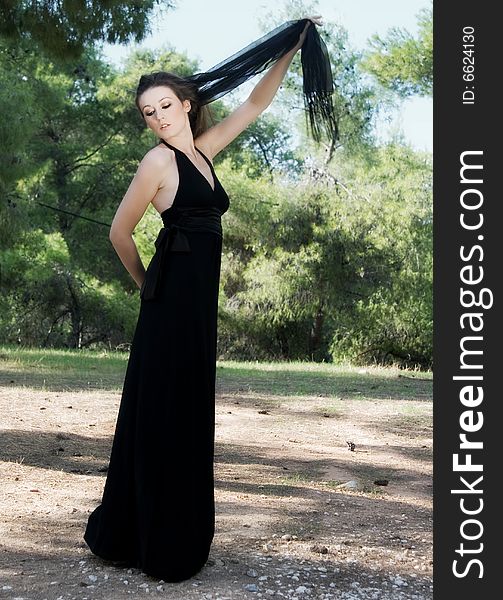 Beautiful female model in the woods wearing a black gown. Beautiful female model in the woods wearing a black gown