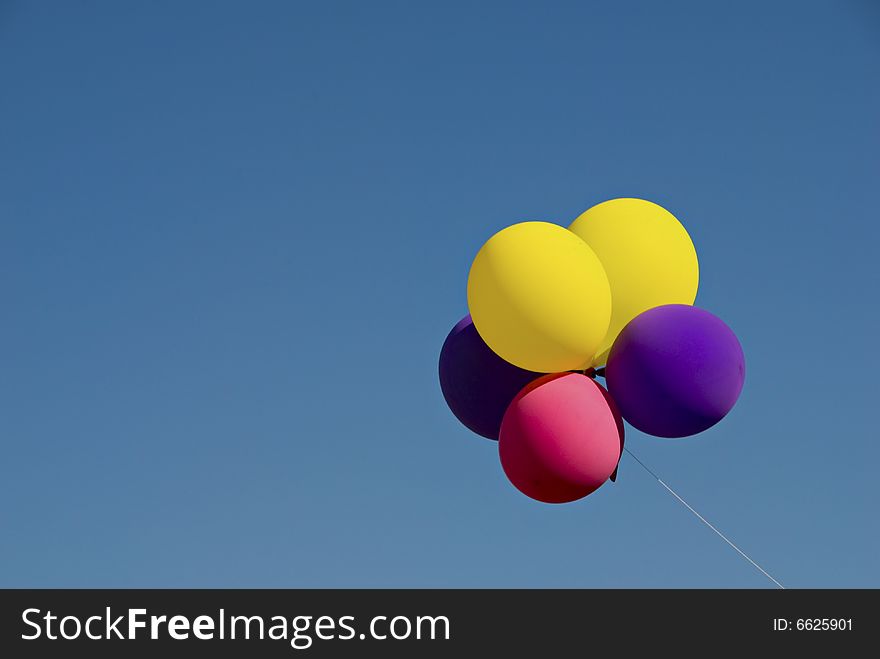 Group of colorful helium inflated balloons floating in clear blue sky with copyspace. Group of colorful helium inflated balloons floating in clear blue sky with copyspace