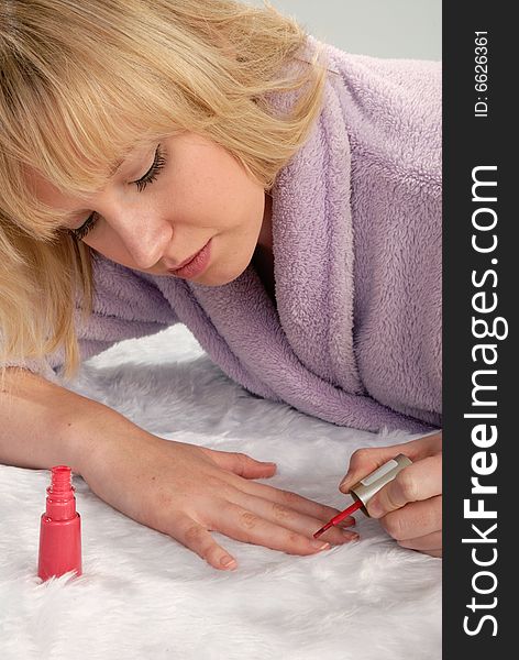 Cute blond woman applying red nail vanrish to her fingernails. Cute blond woman applying red nail vanrish to her fingernails