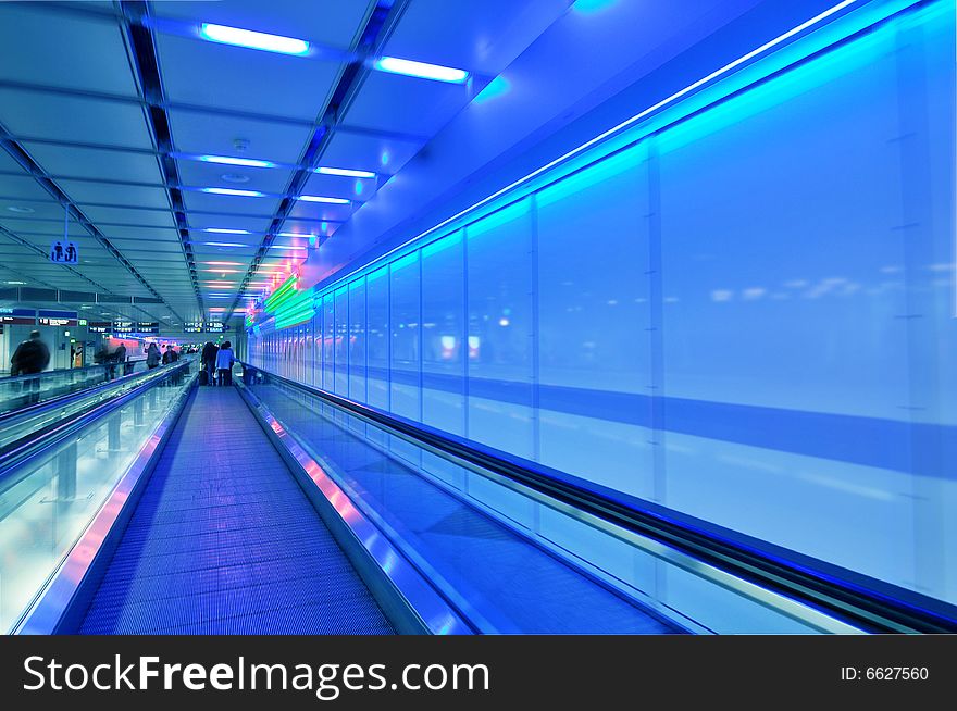 People moving in glass corridor in blue. People moving in glass corridor in blue