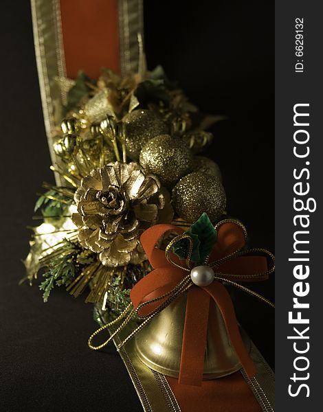 A christmas bell with a pine cone and artificial plants, and a ribbon as a background. Isolated in black. A christmas bell with a pine cone and artificial plants, and a ribbon as a background. Isolated in black.