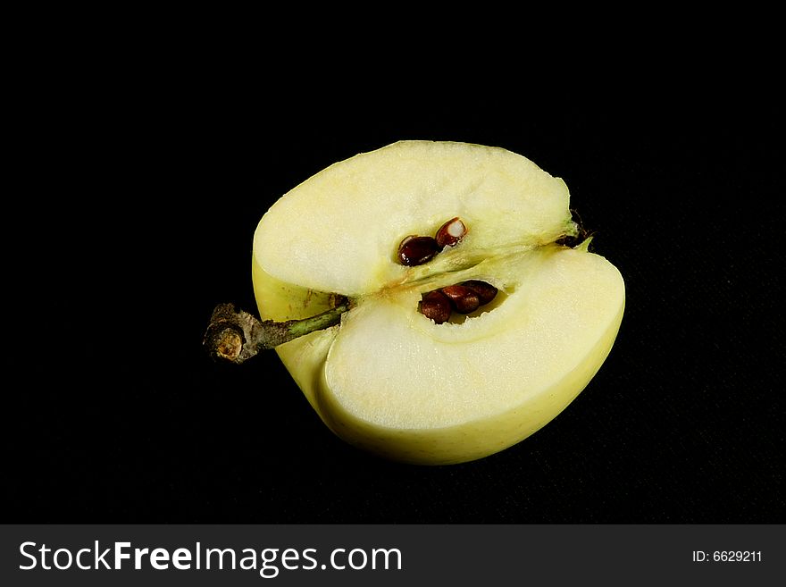 Half of yellow apple with seeds on black. Half of yellow apple with seeds on black