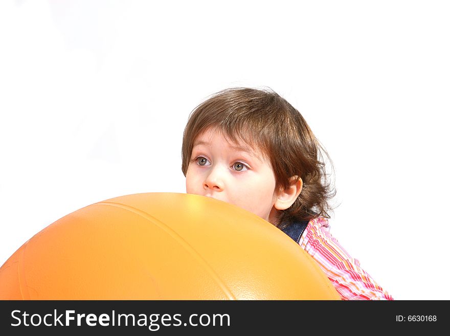 Little girl playing with big orange ball on white ground