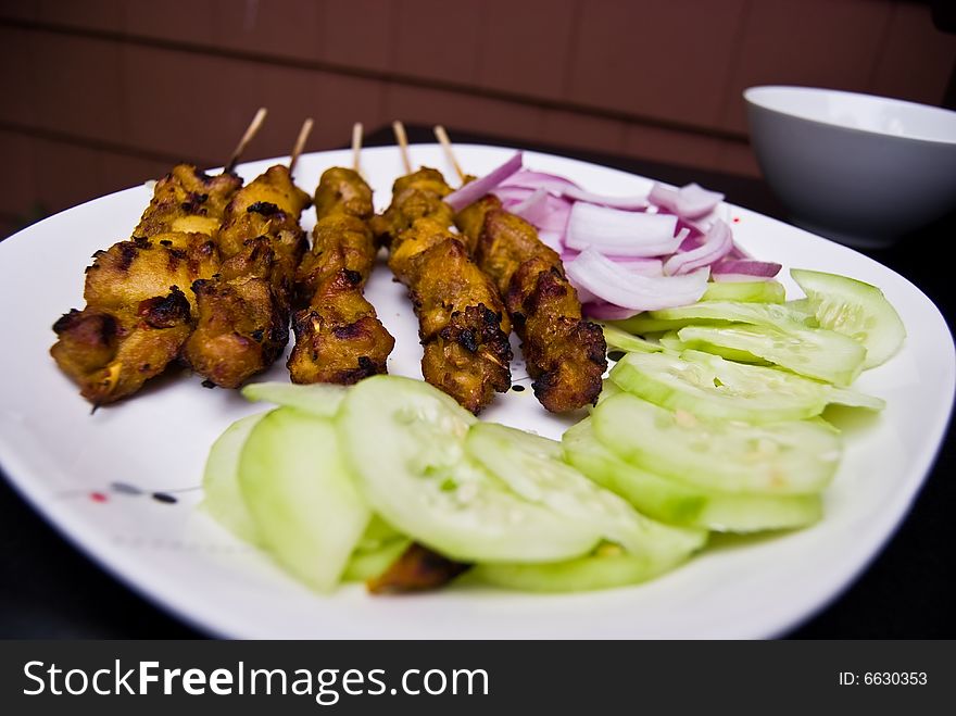 Chicken Satays that have been barbequed, served with sliced onions and cucumber. Chicken Satays that have been barbequed, served with sliced onions and cucumber.