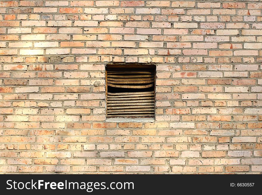Old metal rusty ventilation window on brick wall.