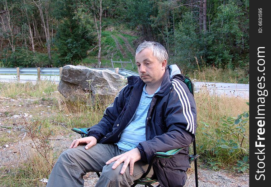 The man, having a rest near road after long driving. The man, having a rest near road after long driving