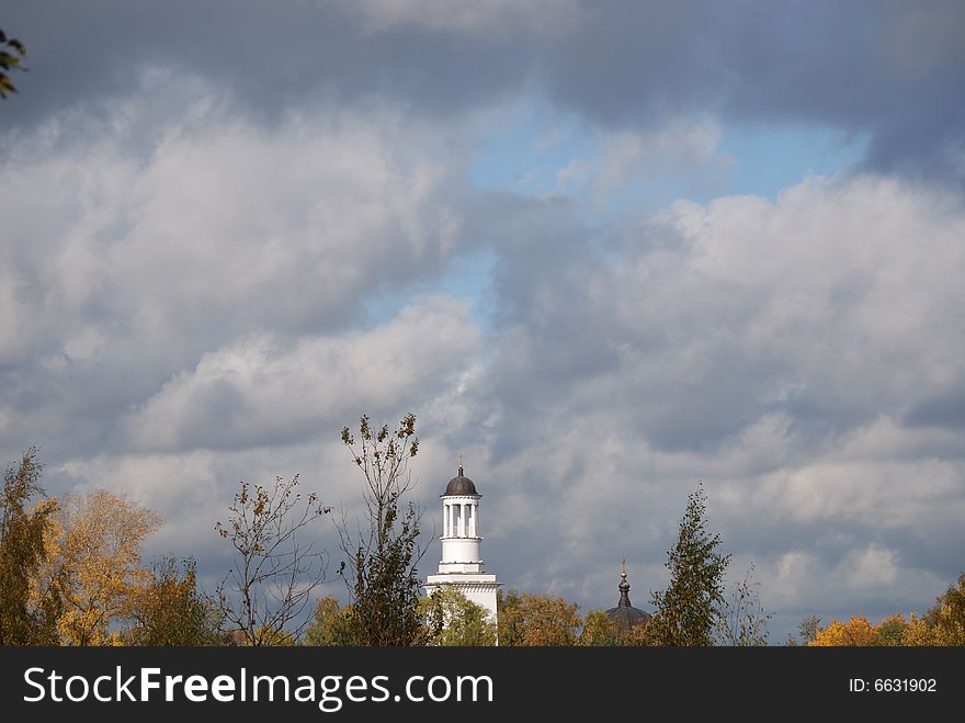 White church, could be seen after trees with an autumn foliage