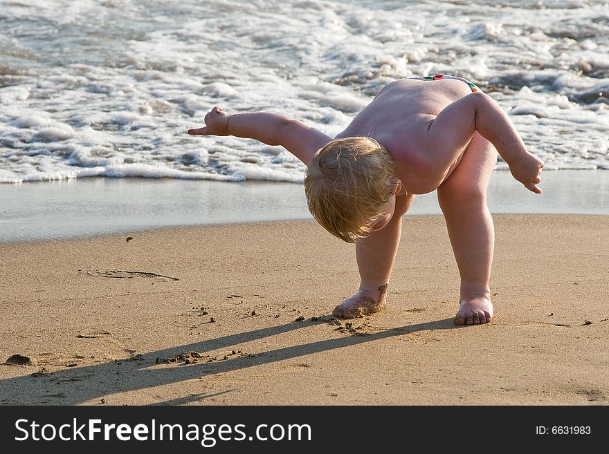 Small child stands having bent down on a beach. Small child stands having bent down on a beach