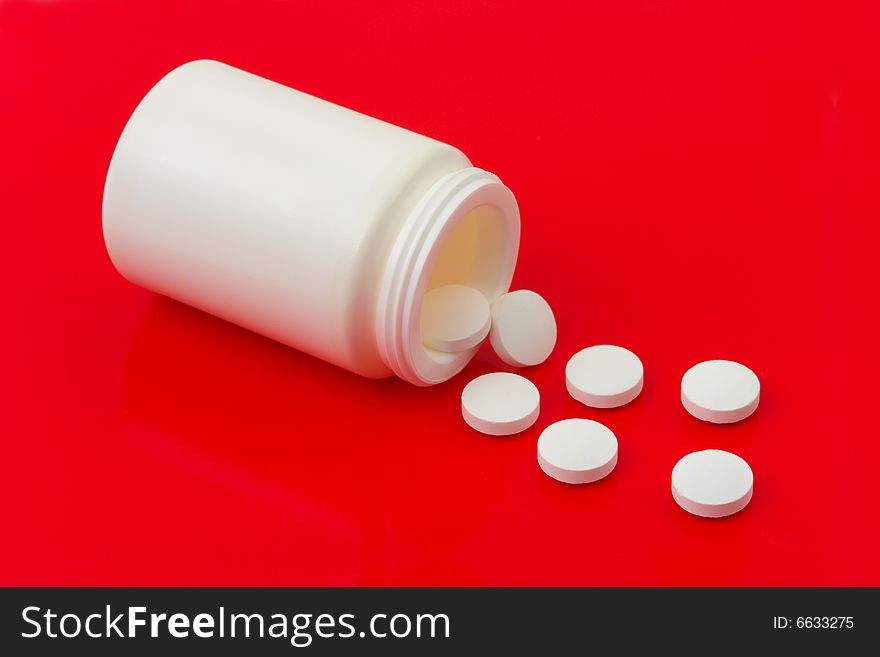 Bottle of pills on red background