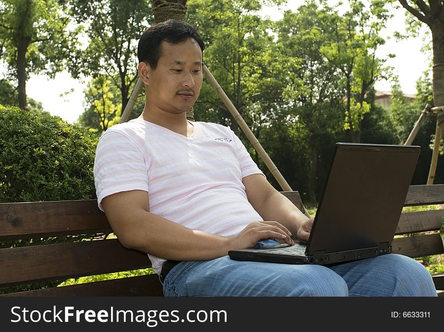 A young man using a laptop in the park