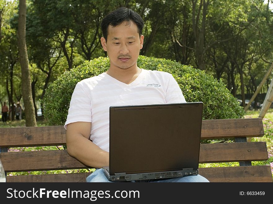 A young man using a laptop in the park