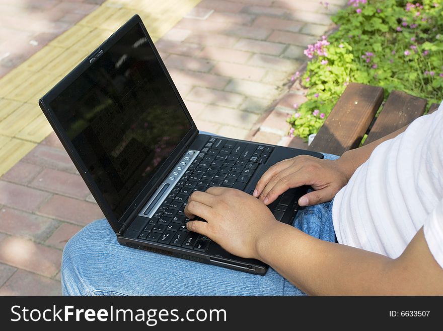 A young man using a laptop in the park