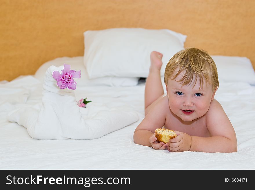 Small child with a cake lays on a bed. Small child with a cake lays on a bed