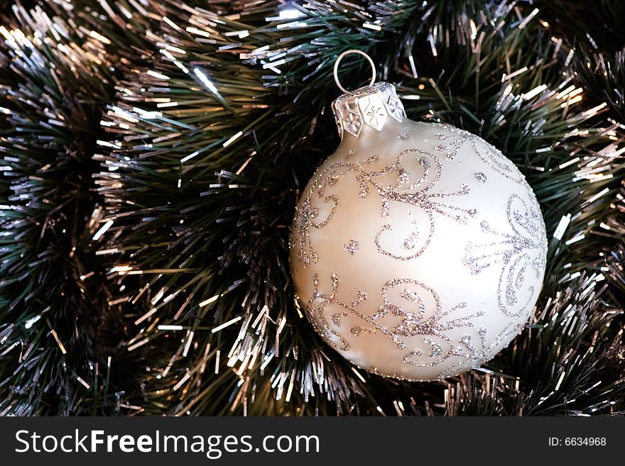 White Christmas bauble in green tinsel. White Christmas bauble in green tinsel