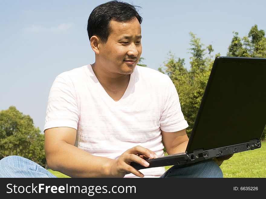 A young man using a laptop outdoors. A young man using a laptop outdoors