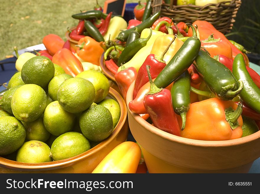 Bowl of freshly picked limes and peppers in a farmers market. Bowl of freshly picked limes and peppers in a farmers market