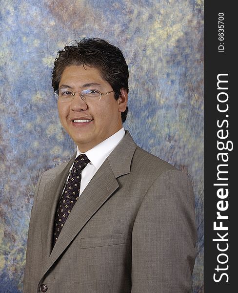 Attractive asian businessman in a suit and glasses against a colored backgrond. Attractive asian businessman in a suit and glasses against a colored backgrond