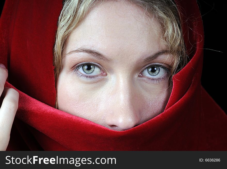 Beautiful young blond woman in closeup with shawl over her face