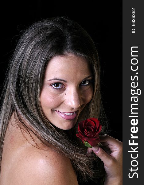 Beautiful young brunette woman holding a red rose a sign of love for valentines or any other special occasion. Beautiful young brunette woman holding a red rose a sign of love for valentines or any other special occasion