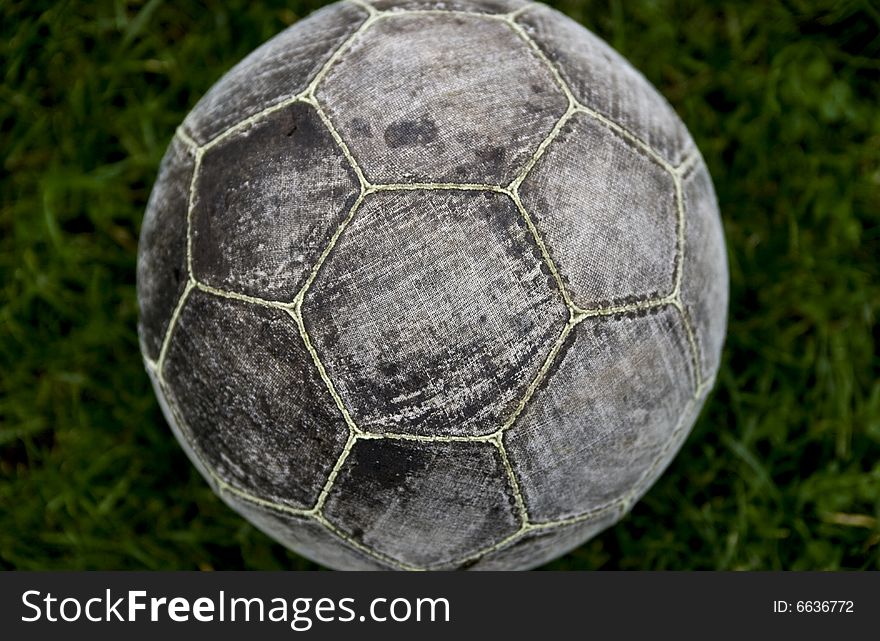 One grey old football on the grass outside. taken close up and on top of the ball.