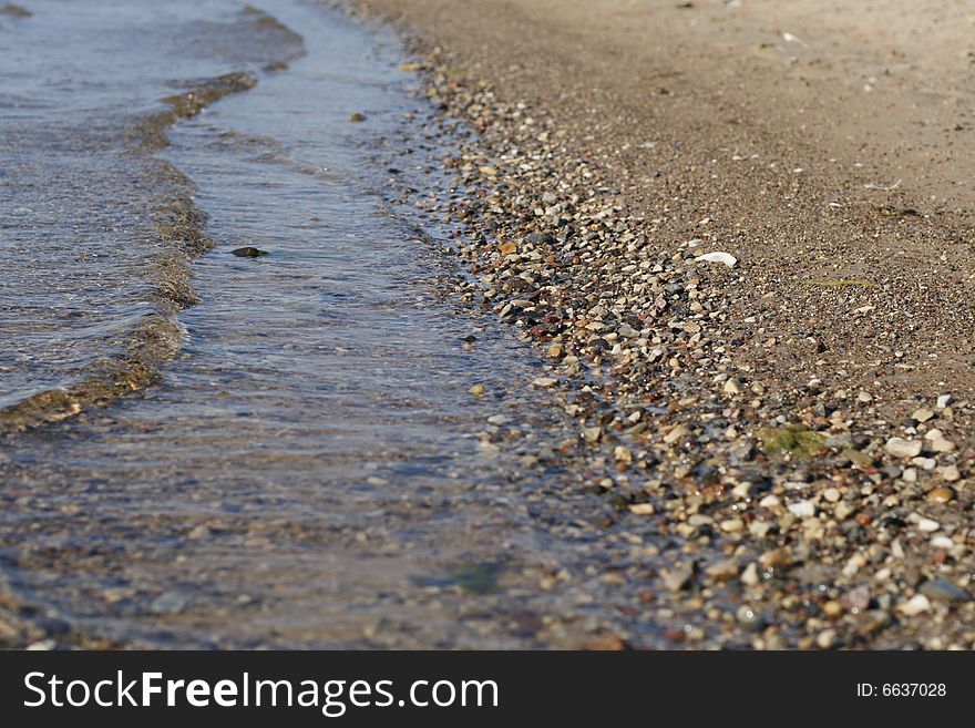 Beach with clear water and wet pebbles - shallow dof. Beach with clear water and wet pebbles - shallow dof