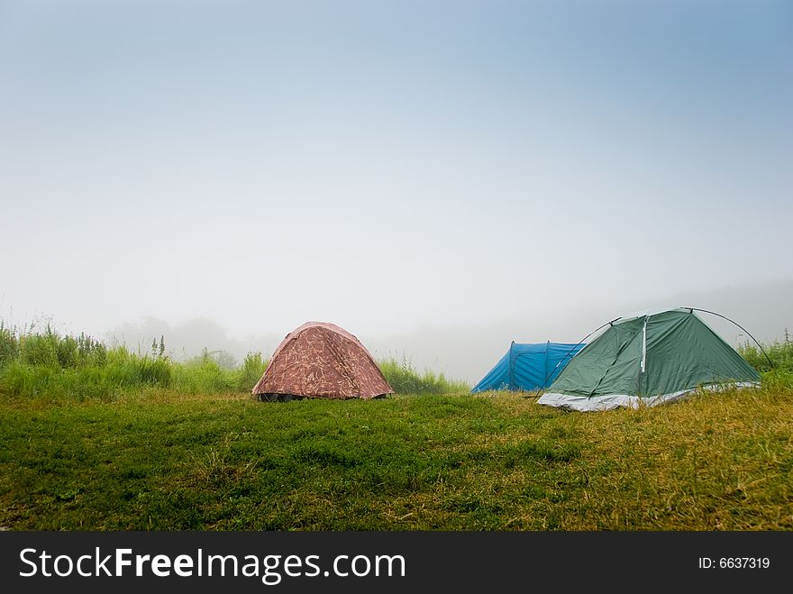 Tourist tents on a grass in a fog