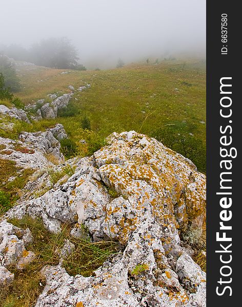 Misty morning meadow in Crimea mountains, Ukraine. Stones on a foreground