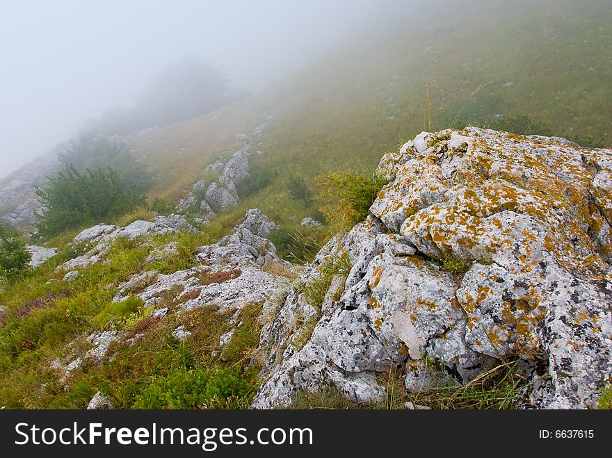 Misty morning meadow in Crimea mountains, Ukraine. Stones on a foreground