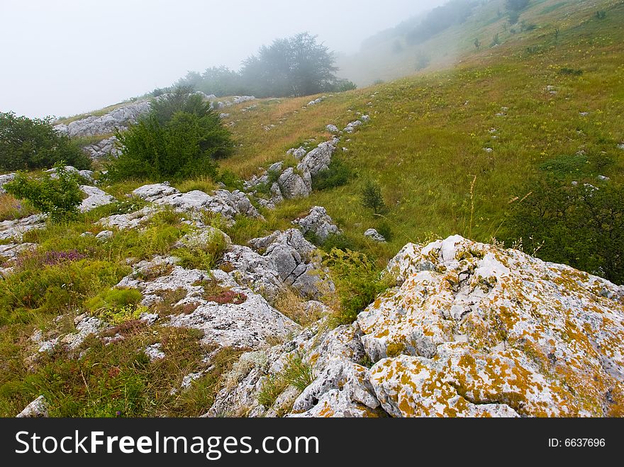 Misty morning meadow in Crimea mountains, Ukraine. Stones on a foreground