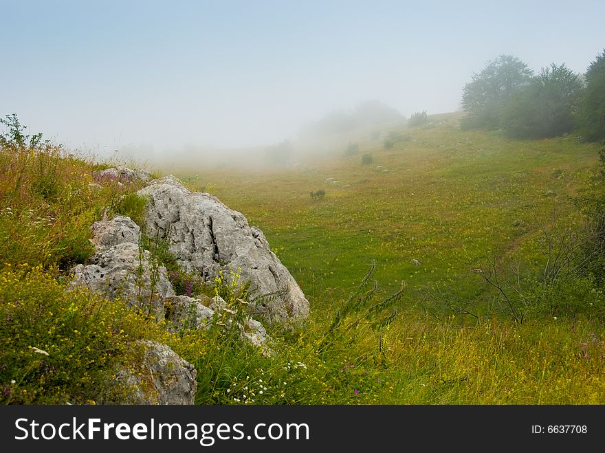 Misty morning meadow in Crimea mountains, Ukraine. Stones on a foreground