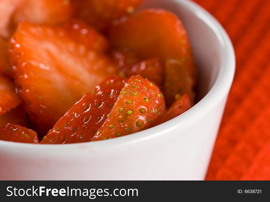 Fresh strawberries in a white pot on a red cloth