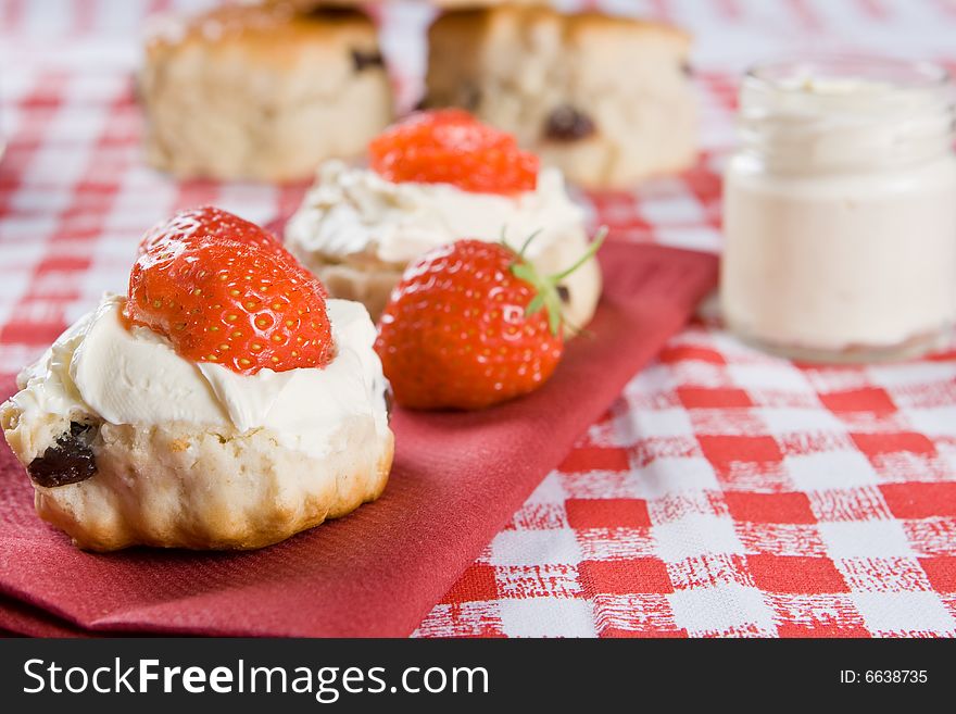 Scones, strawberries and clotted cream on a red napkin