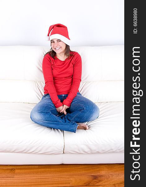 Beautiful young woman with red christmas hat sitting in home sofa. Beautiful young woman with red christmas hat sitting in home sofa