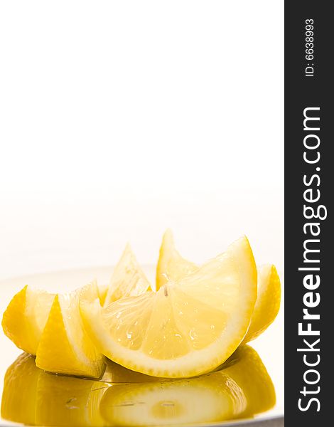 Freshly cut slices of lemon on a shiny plate with a white background. Copy space. Freshly cut slices of lemon on a shiny plate with a white background. Copy space.