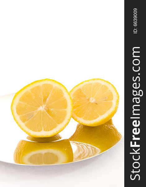Freshly cut slices of lemon on a shiny plate with a white background. Copy space. Freshly cut slices of lemon on a shiny plate with a white background. Copy space.
