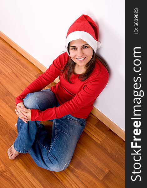 Beautiful young woman with red christmas hat sitting in the home floor